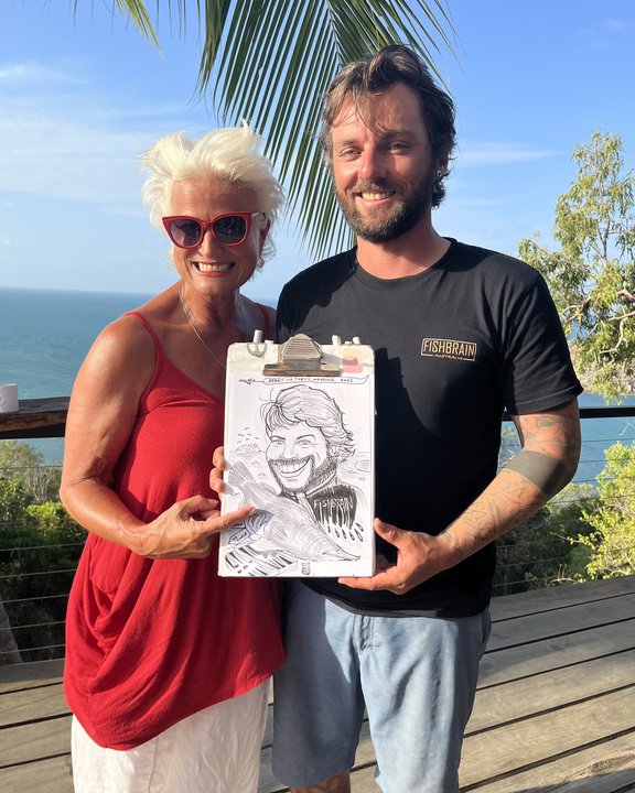 Artist with a guest and his caricature on a terrace by the sea