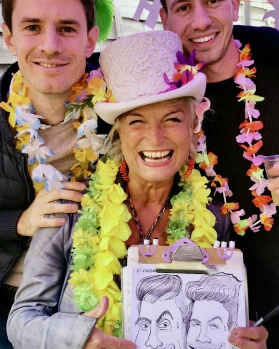 Artist with two guests in leis holding their caricature