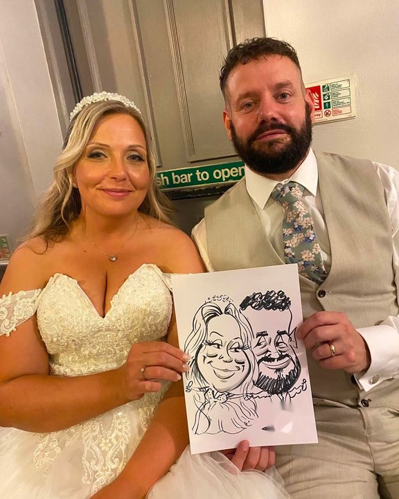 Bride and groom holding their live wedding caricature