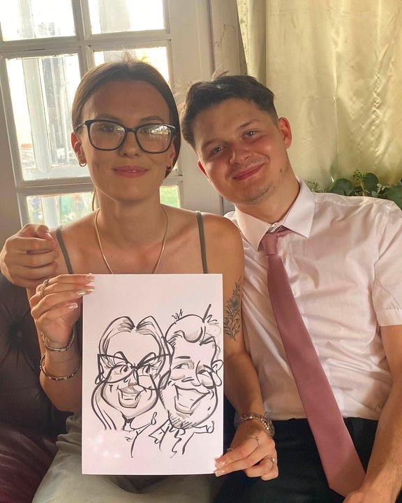 Couple holding their caricature at a wedding