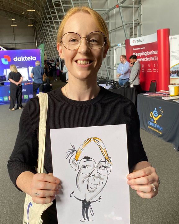 Visitor holding her caricature at an exhibition in an aircraft hangar