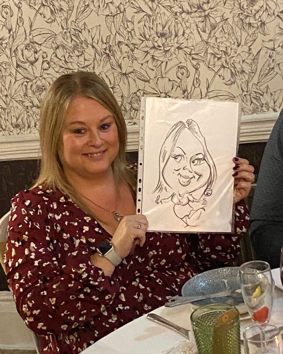 Guest holding her caricature at a long service awards dinner