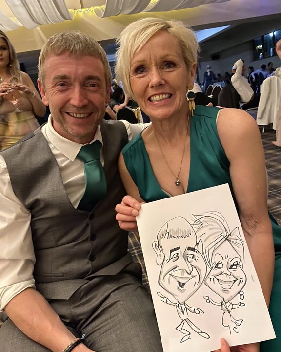 Couple holding their caricature at a charity ball
