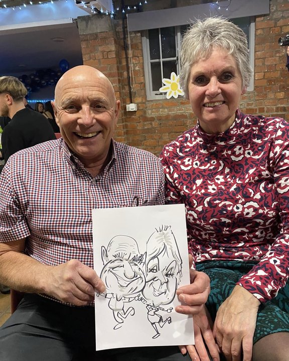 Couple holding their caricature at a Christmas party