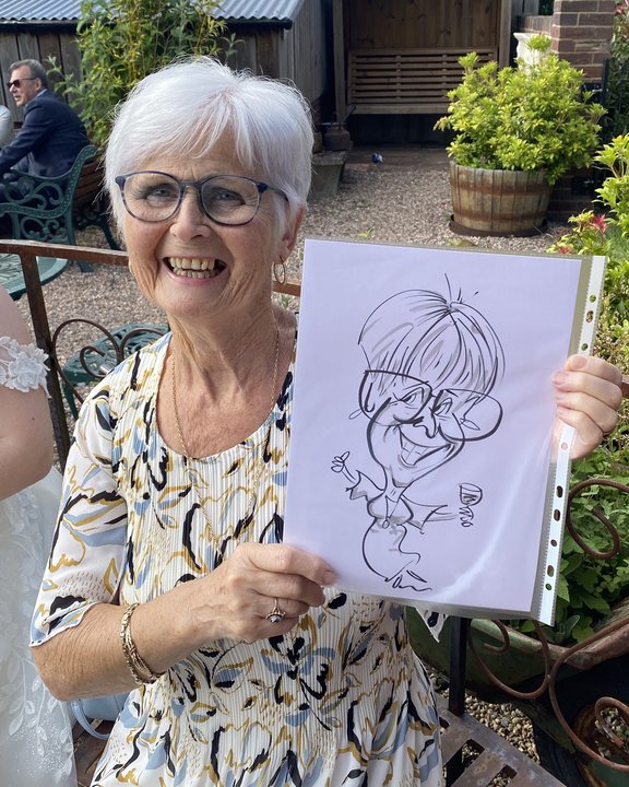 Guest holding her caricature at a garden party