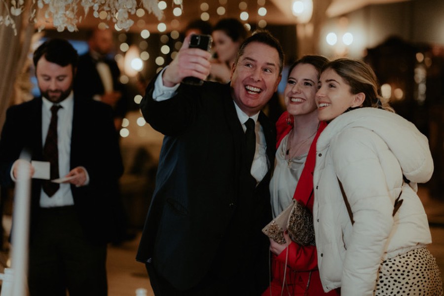 The Gentleman Pickpocket taking a selfie with smiling guests at a Christmas party