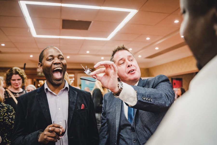 A corporate event guest roaring with laughter as the Gentleman Pickpocket performs a trick