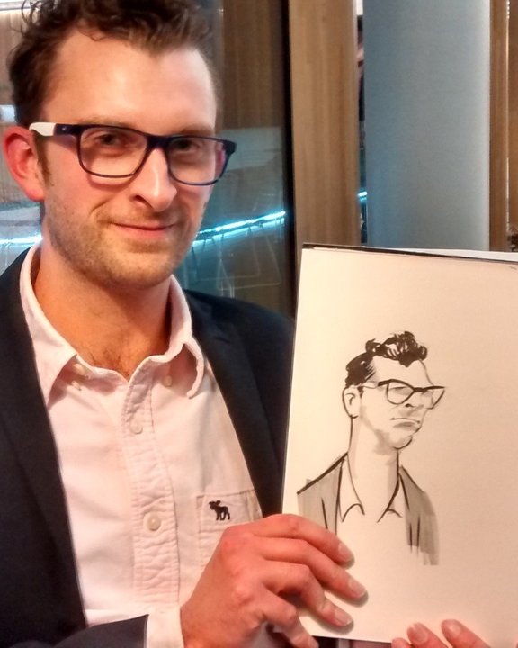 Guest in glasses holding his caricature at a Christmas party