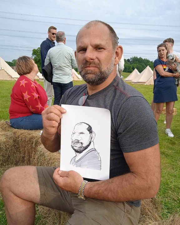 Guest holding his caricature at an outdoor festival