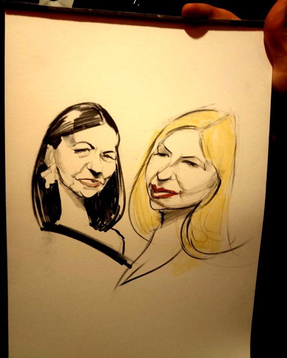 Two guests holding up their colour caricature