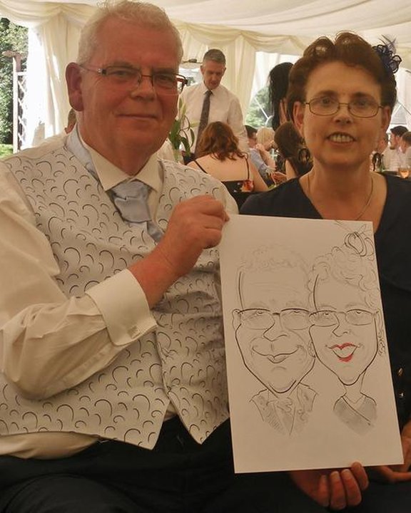 Couple holding their caricature at a wedding in a marquee