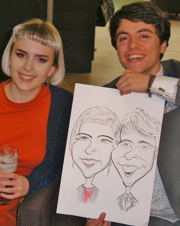 Young couple holding their caricature at a wedding reception