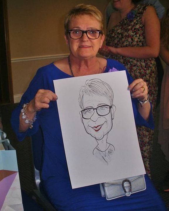 Wedding guest in blue holding her caricature