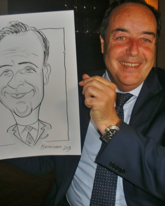 Guest in a suit holding his caricature at an evening reception