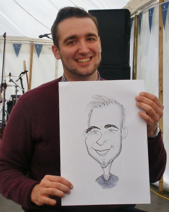 Guest holding his caricature in a marquee