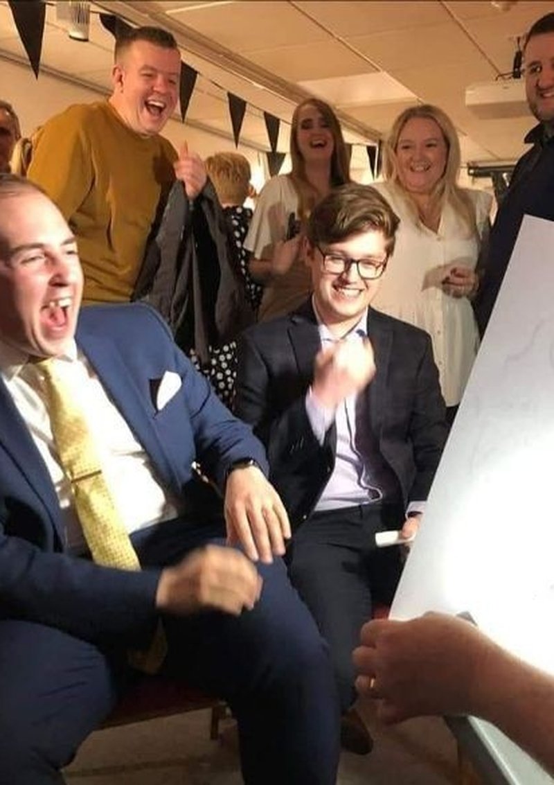 Wedding guests laughing as their caricature is revealed