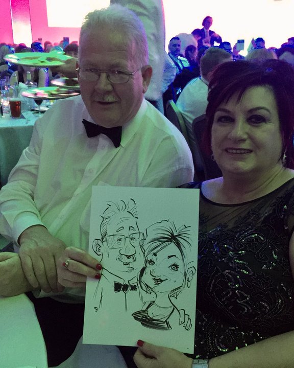 Couple at a gala dinner holding their live caricature