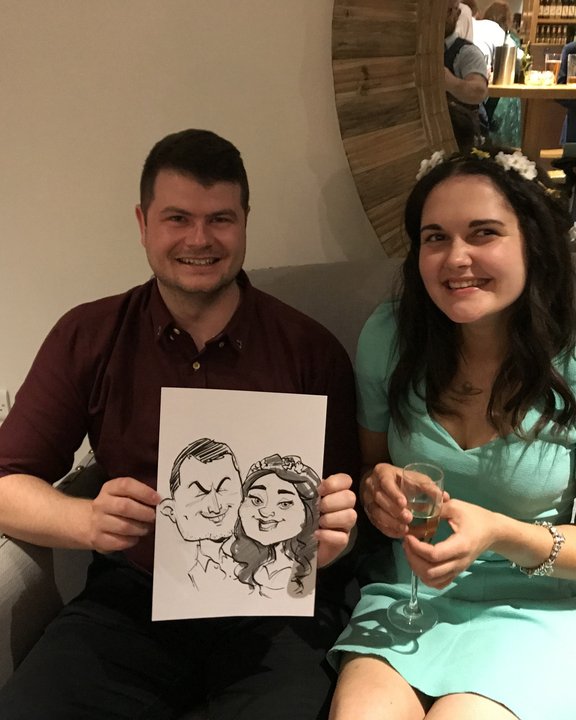 Couple holding their caricature in a hotel lounge