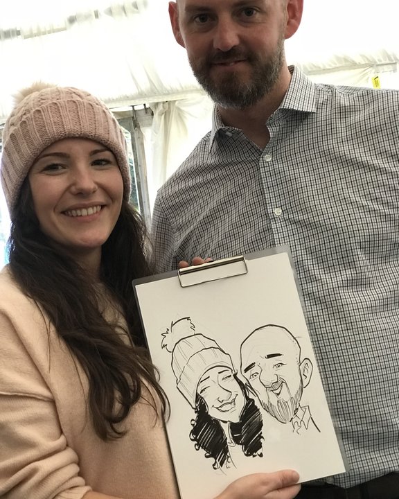 Couple holding their caricature in a marquee