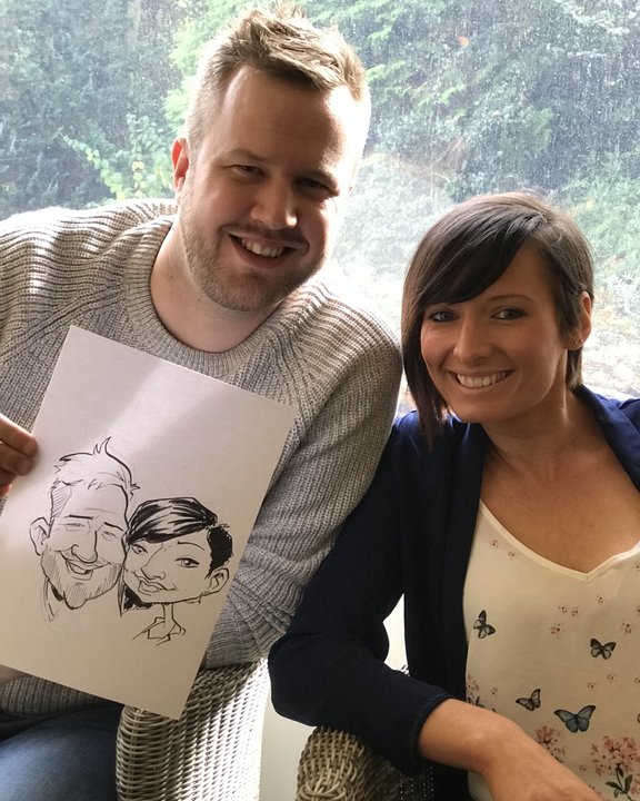 Couple holding their caricature outdoors
