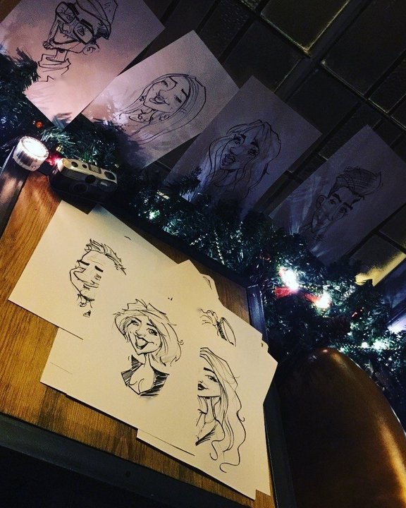 Finished caricatures laid out on a table at a Christmas party