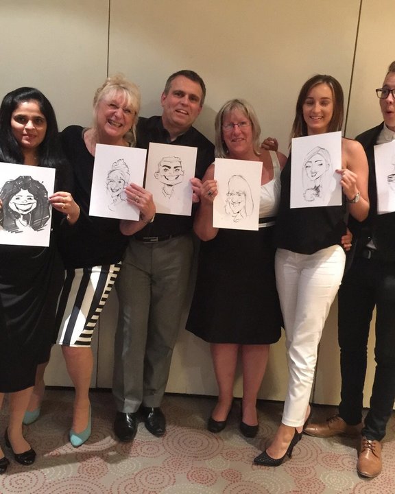 Office team holding their caricatures at a staff party