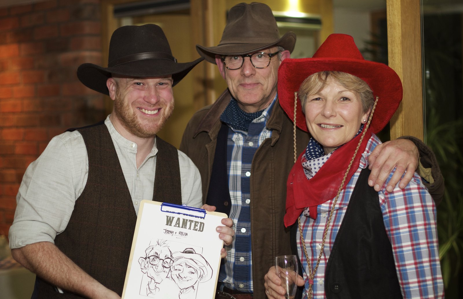 Jolly Caricatures with two guests in Western costume holding their wanted-poster caricature