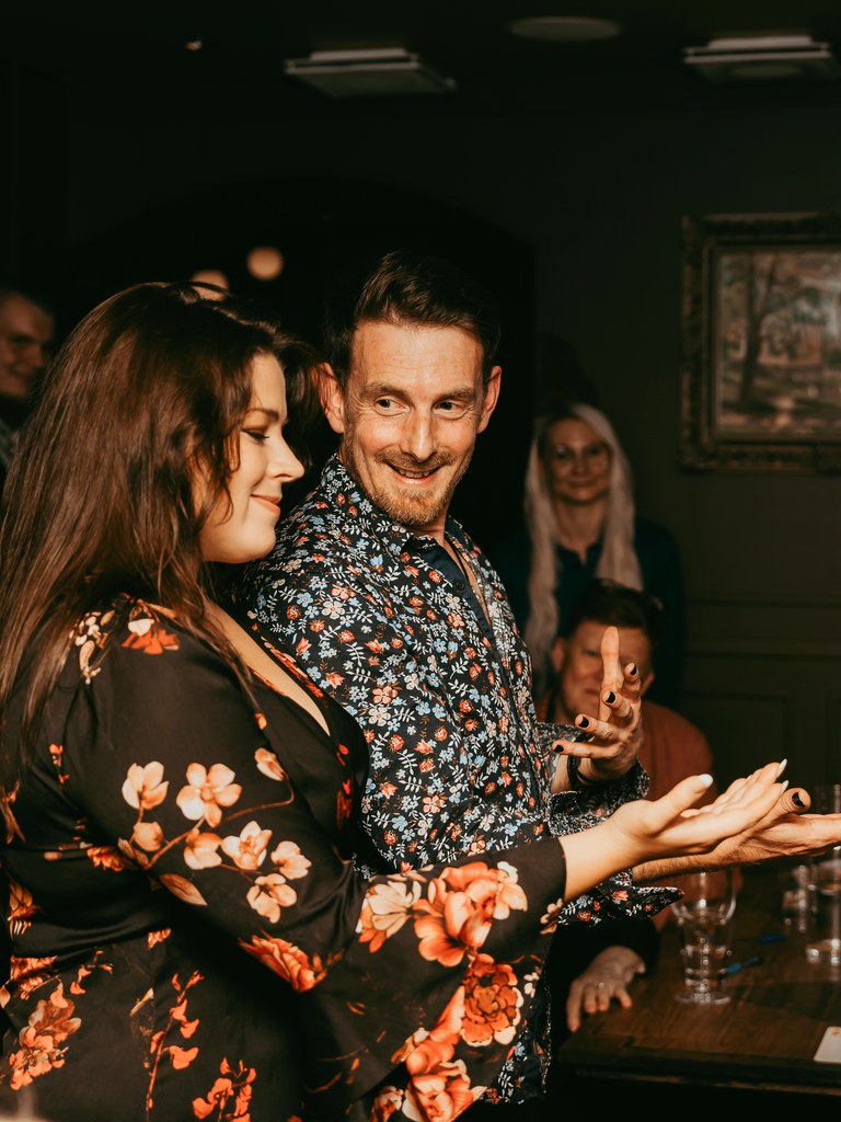 The Artful Pickpocket, a pickpocket and close-up magician in a floral shirt, performing for a delighted guest at an evening party