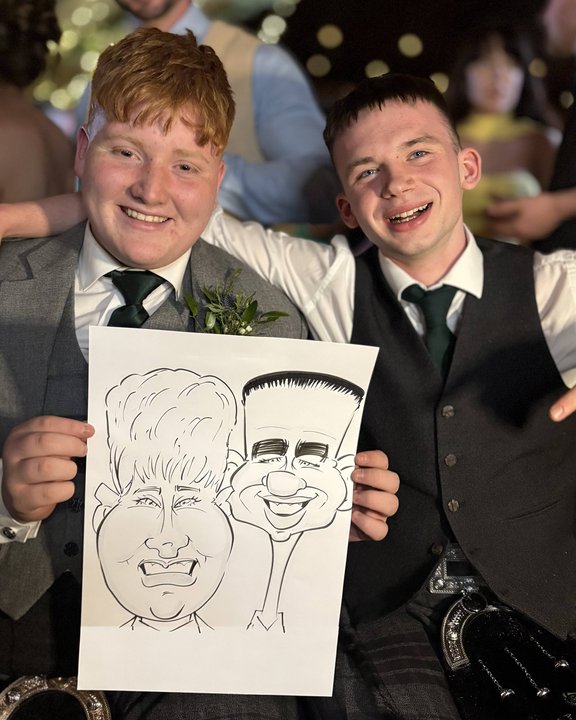 Two wedding guests in kilts holding their shared caricature