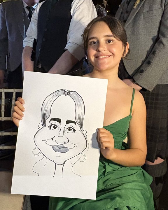 Wedding guest in a green dress holding her caricature