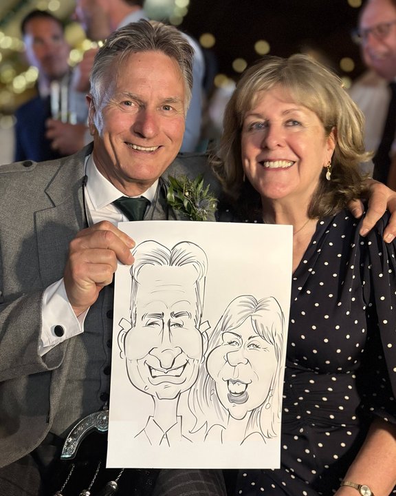 Couple at a wedding holding their live caricature