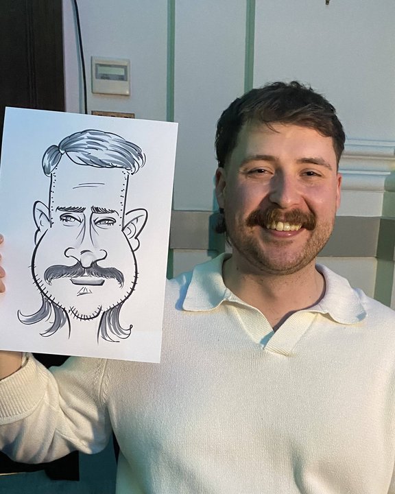 Guest with a moustache holding his live caricature