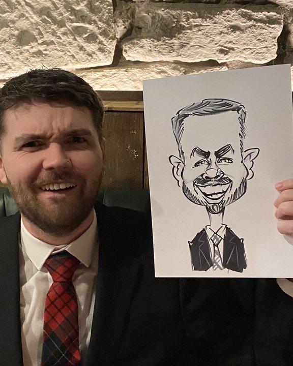 Guest in a tartan tie holding his caricature at a party