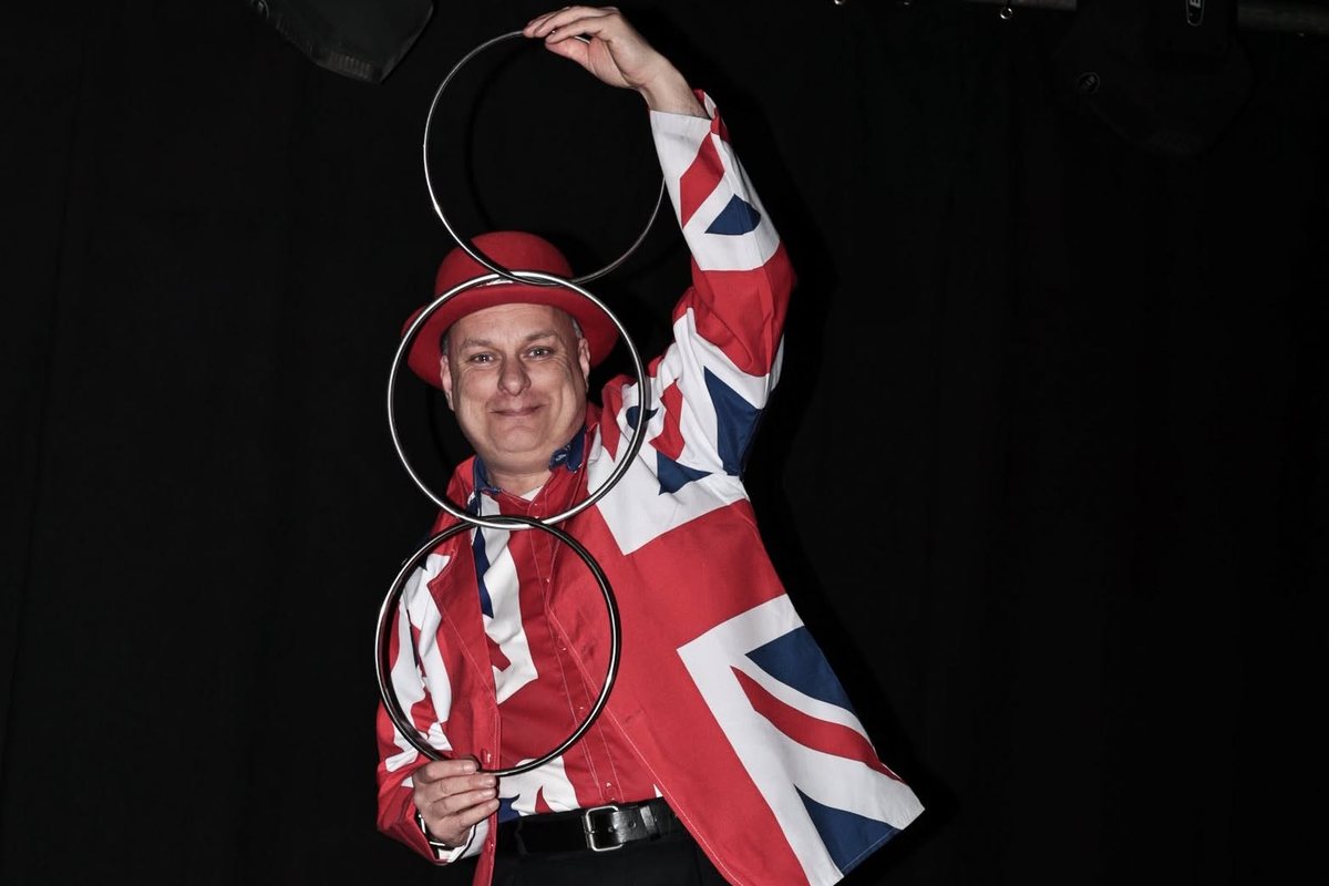 Showtime Magic on stage in a Union Jack jacket and red bowler hat, linking steel rings