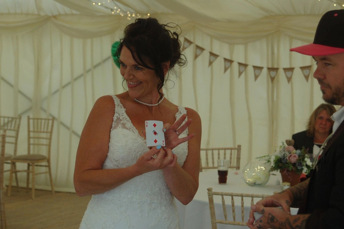 A bride holding up her signed card in a wedding marquee