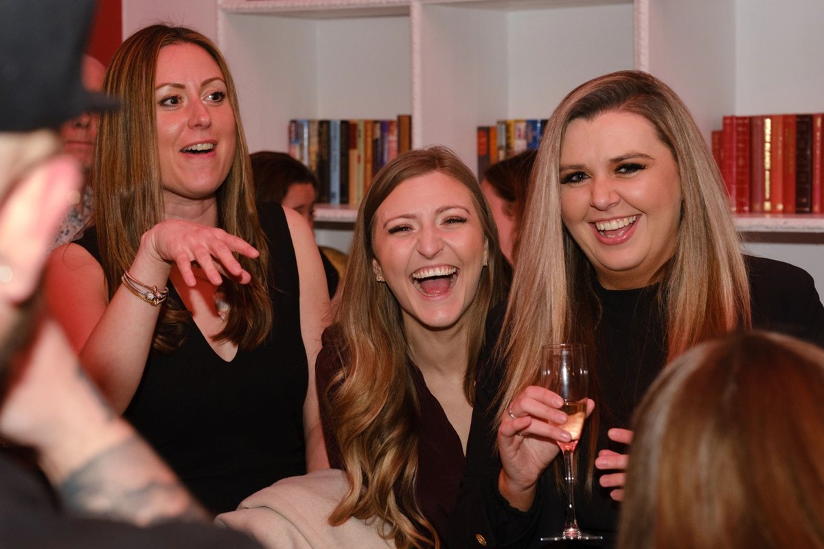 Three guests laughing out loud at a party after a magic trick