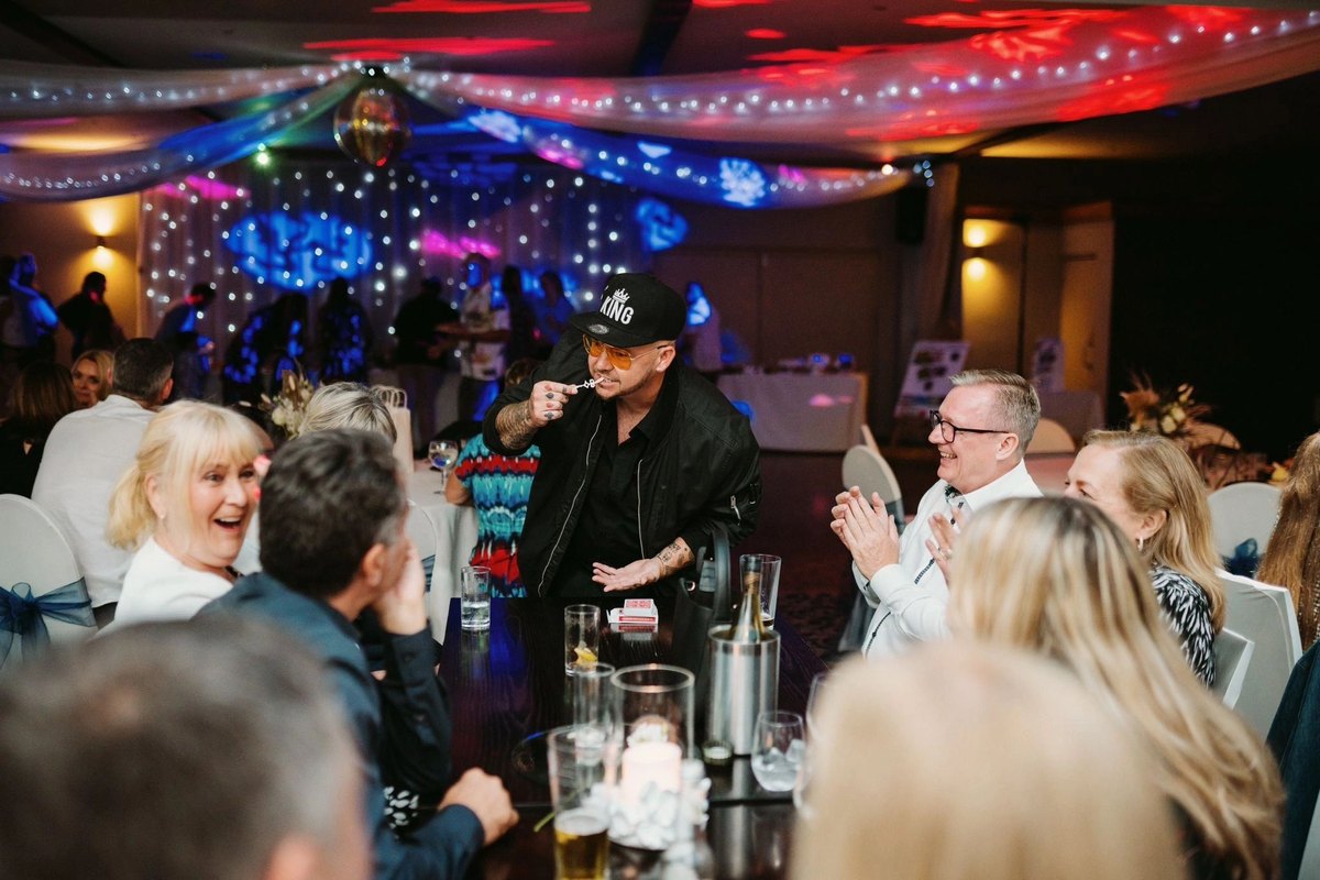 Party guests laughing and applauding as Streetwise Magic performs at their table