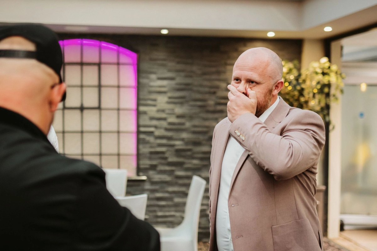 A wedding guest with his hand over his mouth after a close-up magic trick