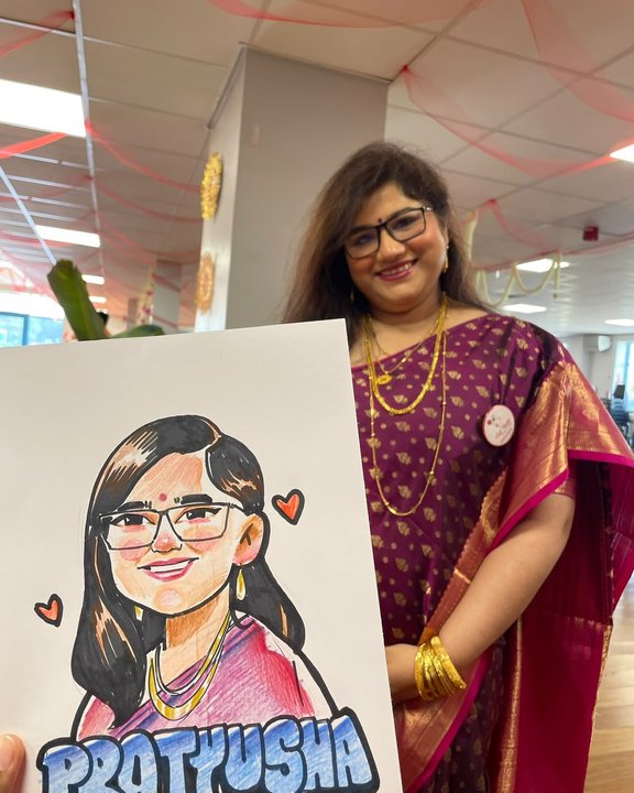 Guest in a sari holding her colour caricature at a community celebration