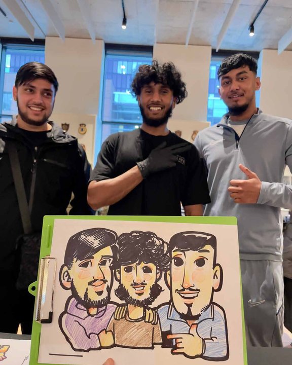 Three friends holding their group caricature at an event