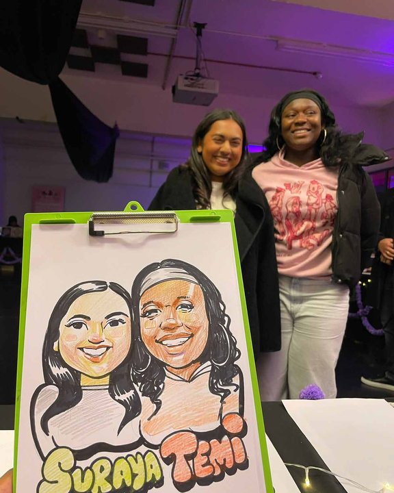 Two friends with their colour double caricature at an evening event