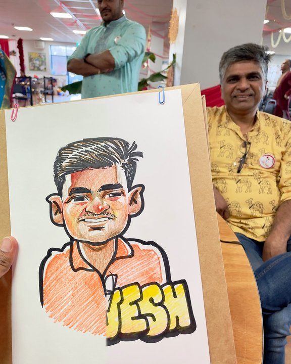 Guest seated beside his colour caricature at a community event