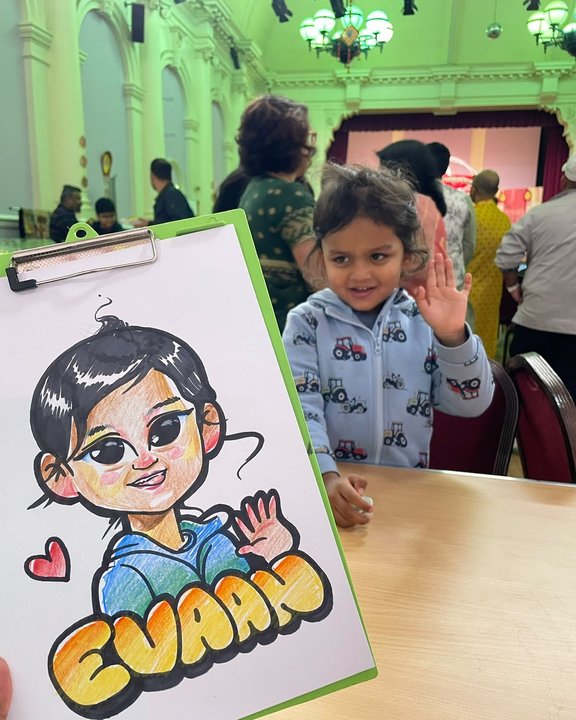Young boy waving beside his colour caricature at a party