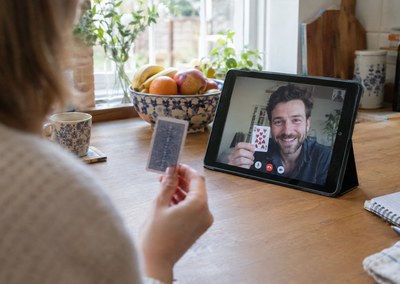 Guest holding up a playing card to a magician on a tablet video call